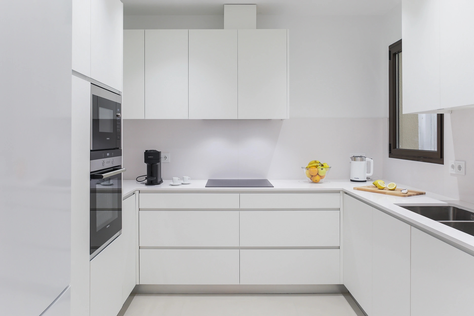 Fotografía de cocina minimalista en blanco con electrodomésticos integrados y encimera despejada en Atelier Apartments
