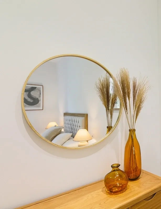 Fotografía de tocador con espejo redondo, jarrones ámbar y decoración en un dormitorio de Atelier Apartments.