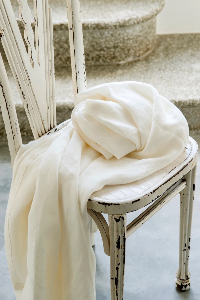 Colección Haytor de Les Créations de la Maison Collection de Grupo Lamadrid. Ventanal con cortinas de la colección y una silla con el tejido blanco premium de la colección.