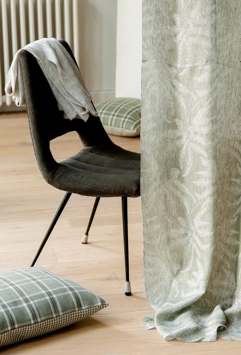 Colección Fingle de Les Créations de la Maison Collection de Grupo Lamadrid. Silla premium con tejidos de colores verde pálido encima y un cojín en el suelo. 
