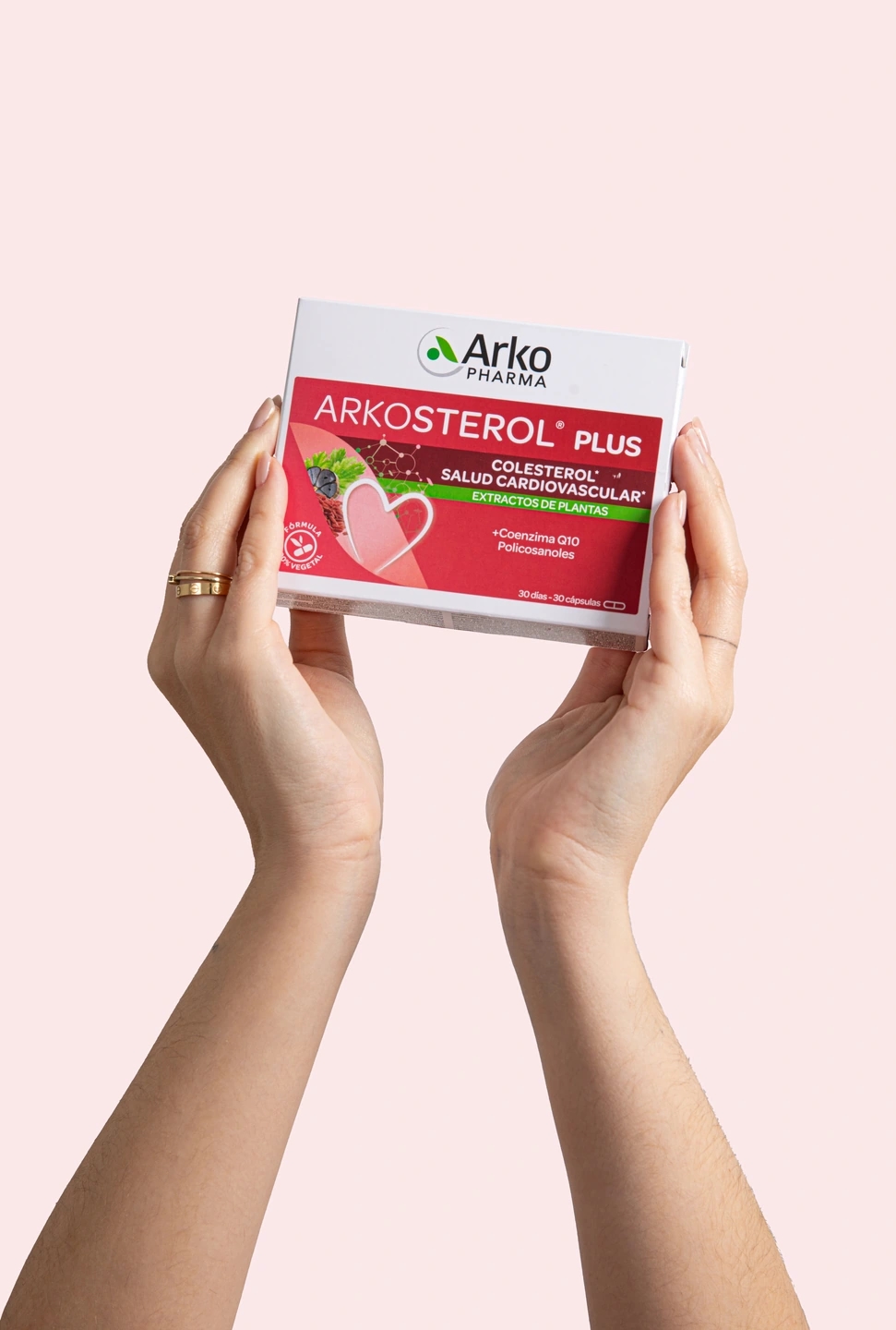 Manos sujetan una caja de Cis colesterol en fondo rosa, producto de la farmacéutica Arkopharma para una sesión fotográfica creativa en Madrid.