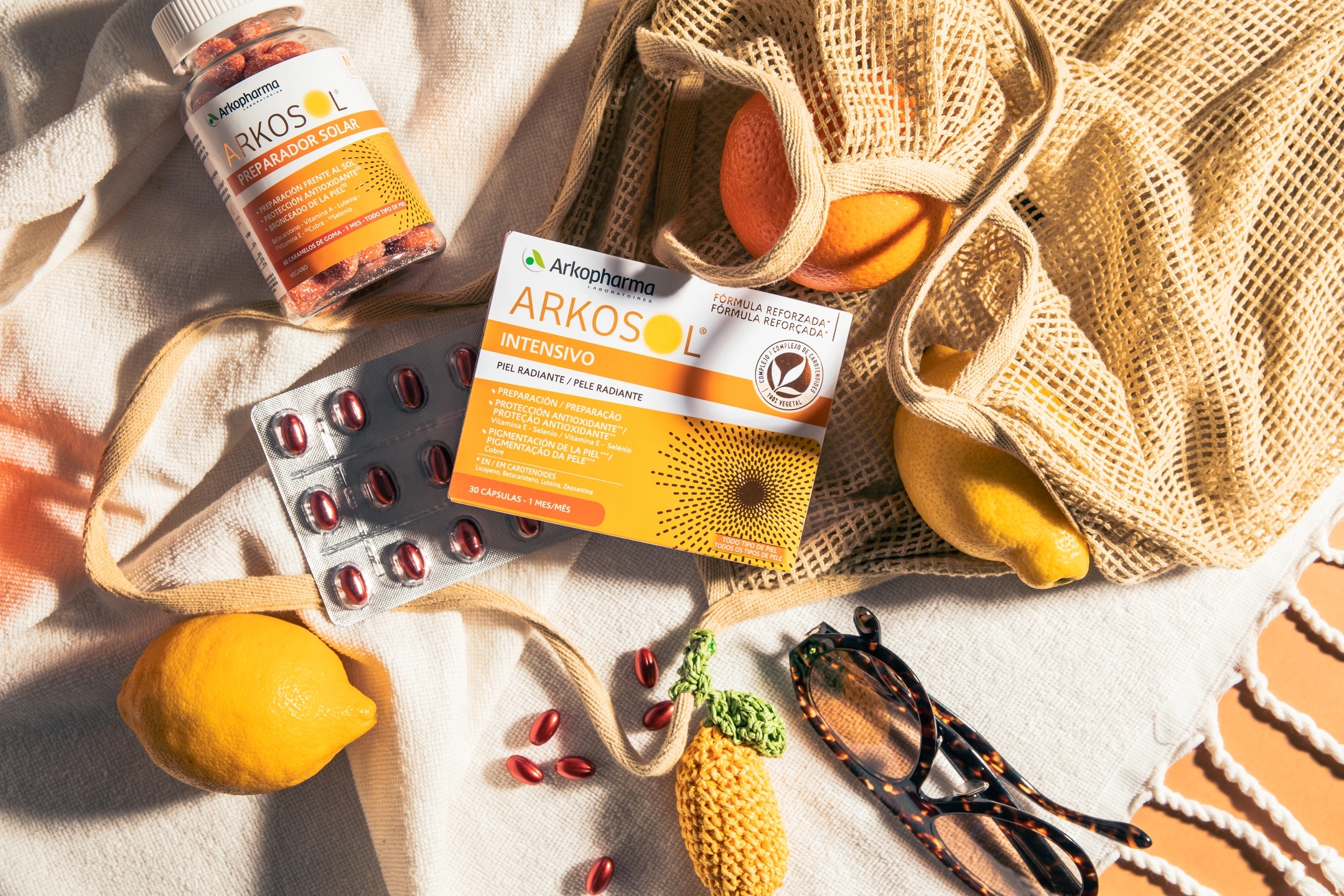Productos de la gama Arkosol encima de toalla de playa con elementos playeros y tonos amarillos, products de la farmacéutica Arkopharma para una sesión fotográfica creativa en Madrid.