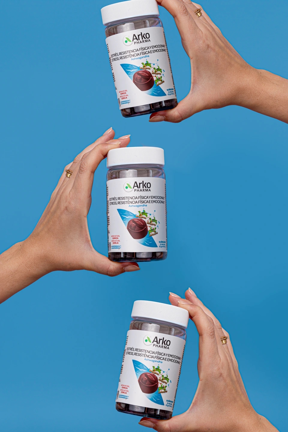manos sujetando botes de gummies contra el estrés físico y emocional, producto de la farmacéutica Arkopharma para una sesión fotográfica creativa en Madrid.