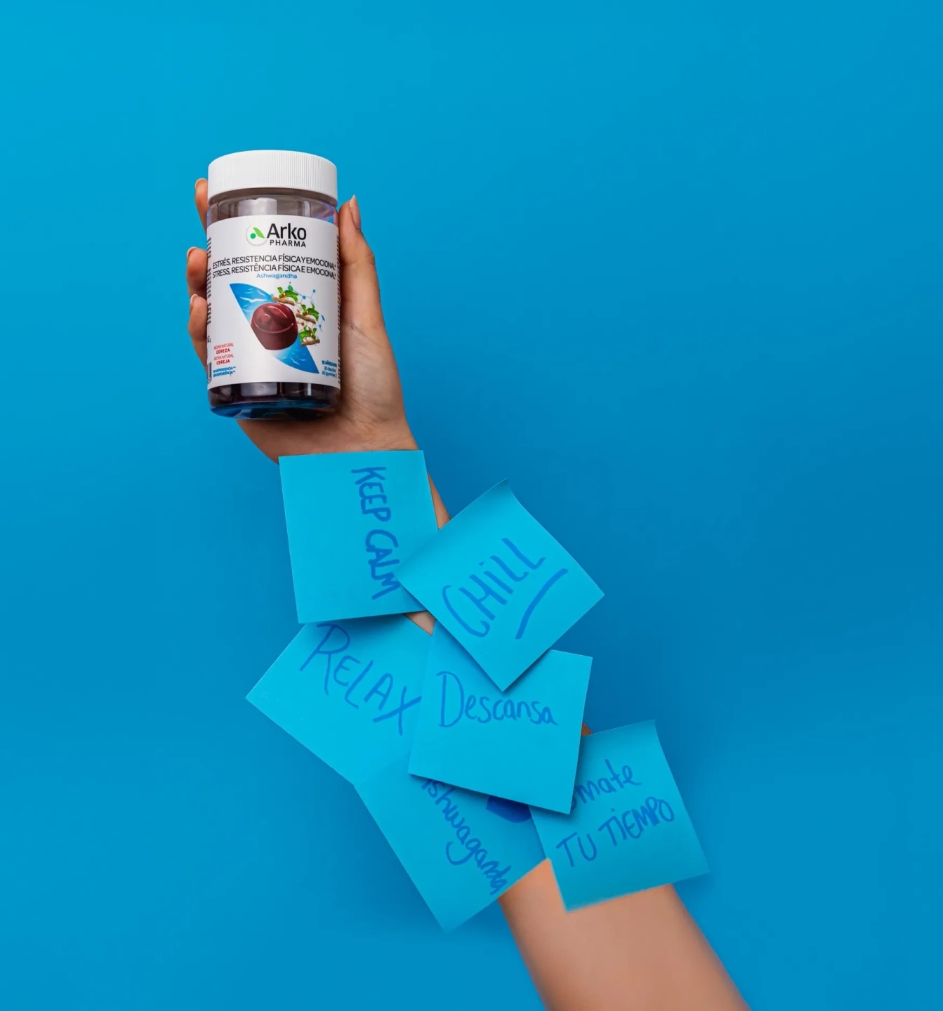 Mujer sujeta un bote de gummies de Ashwahanda con postits estresantes, producto de la farmacéutica Arkopharma para una sesión fotográfica creativa en Madrid.