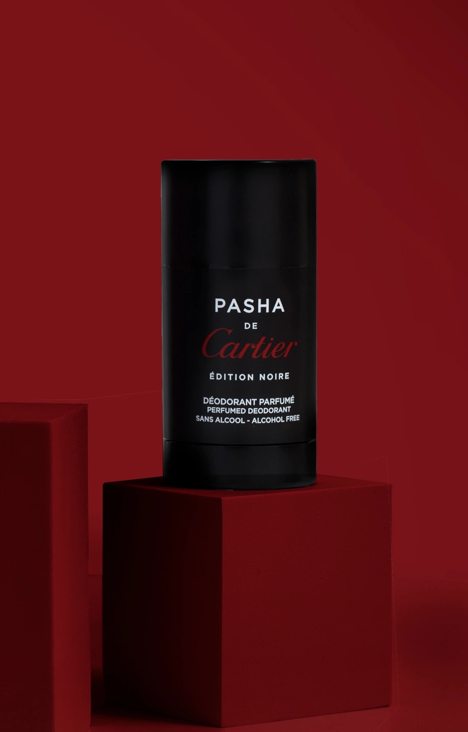 Composición oscura del desodorante Cartier Pasha en fondo rojo oscuro. Fotografía para la marca de perfumerías Éclair.