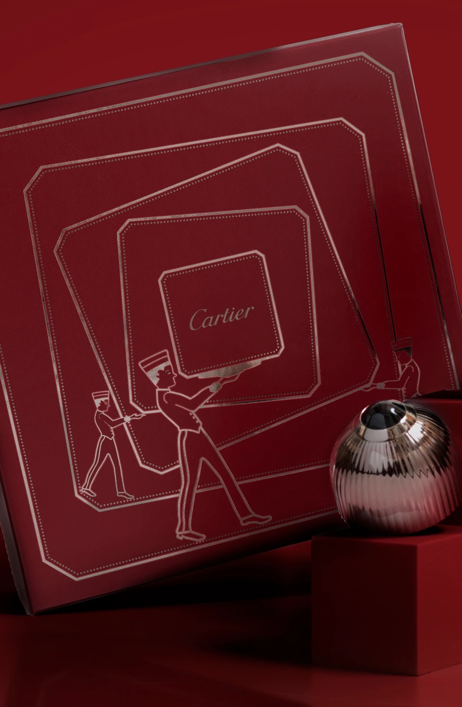 Composición oscura del perfume Cartier PASHA, con la caja en la que viene envuelto. Fondo rojo oscuro. Fotografía para la marca de perfumerías Éclair.