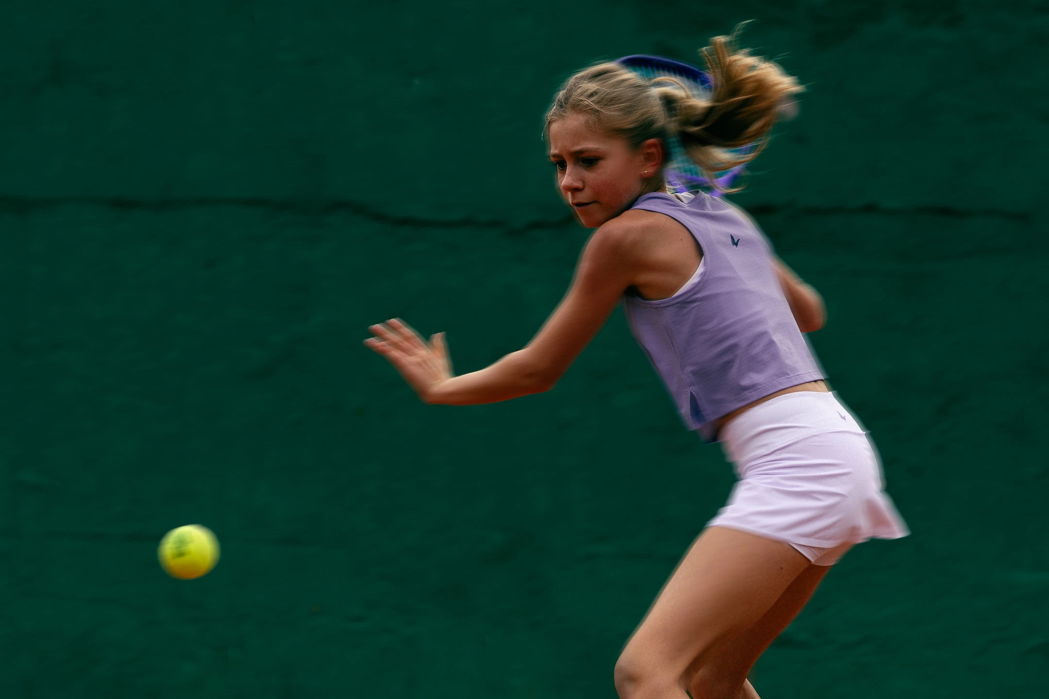 adolescente jugando a tenis en una pista profesional de tierra batida con equipación de la marca ROGGIO de color blanco y lila