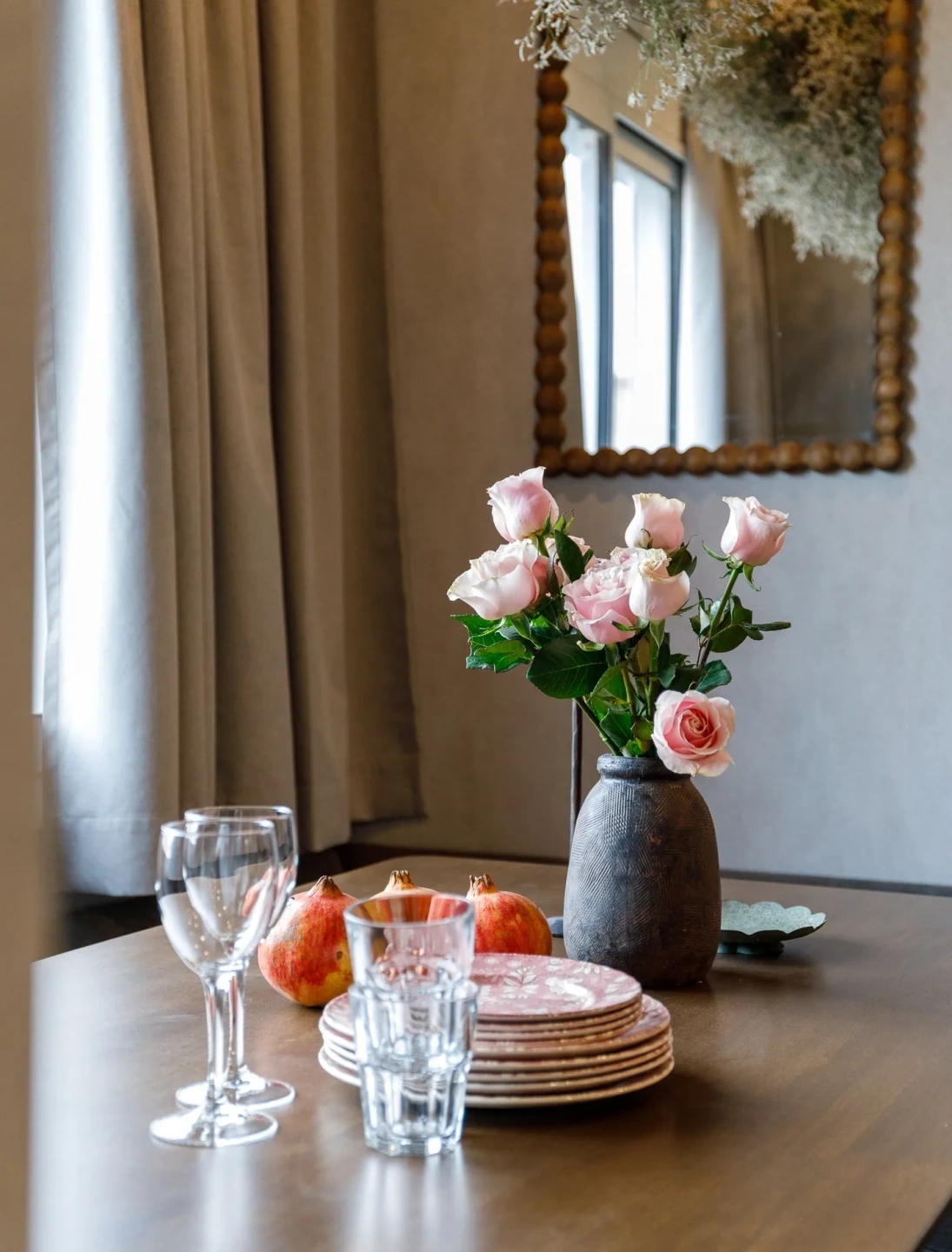 buqué de rosas con platos y copas en mesa de madera. Luz íntima y estilismo cuidado.