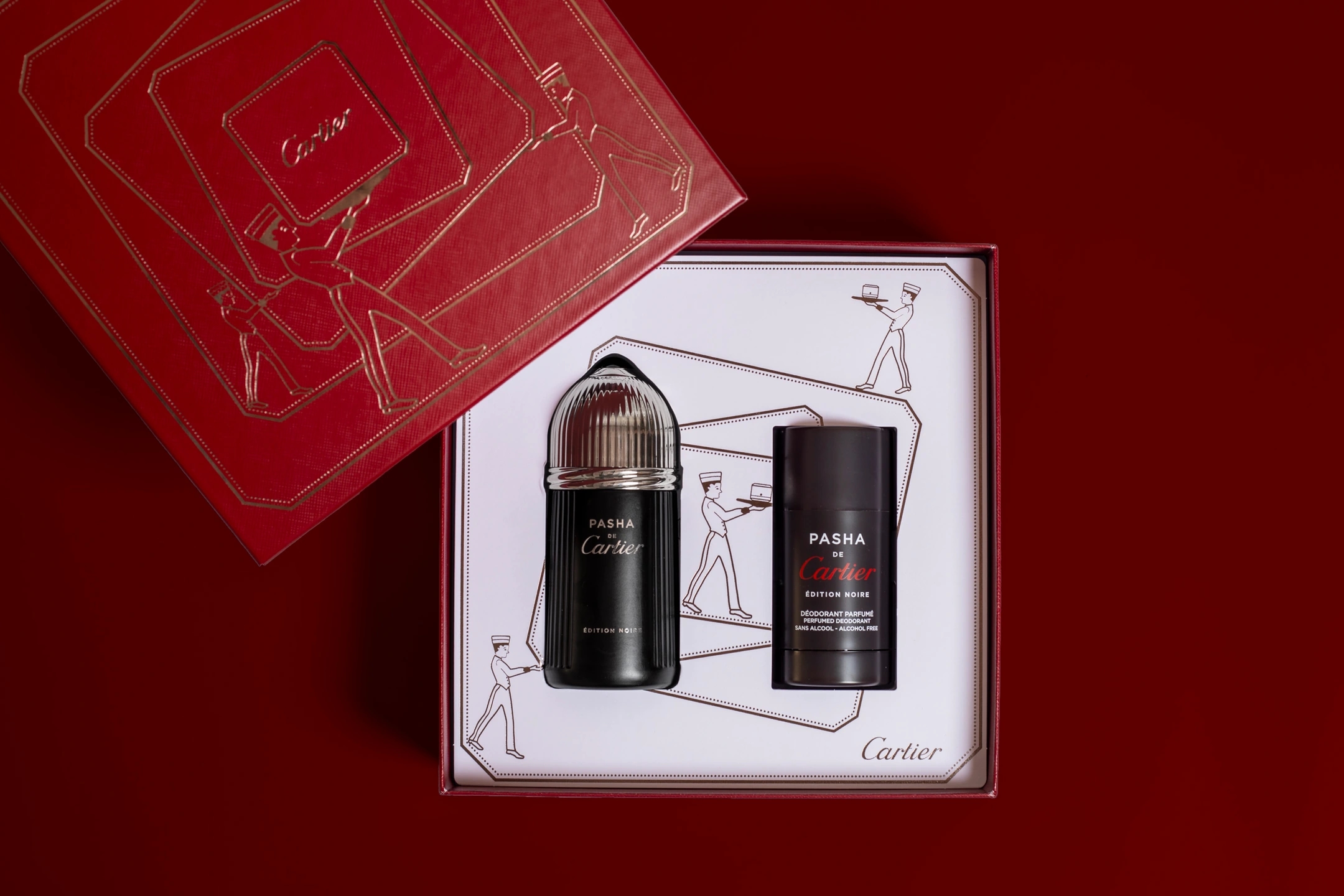 Composición oscura del perfume Cartier PASHA, con el desodorante y la caja en la que viene envuelto. Fondo rojo oscuro. Fotografía para la marca de perfumerías Éclair.