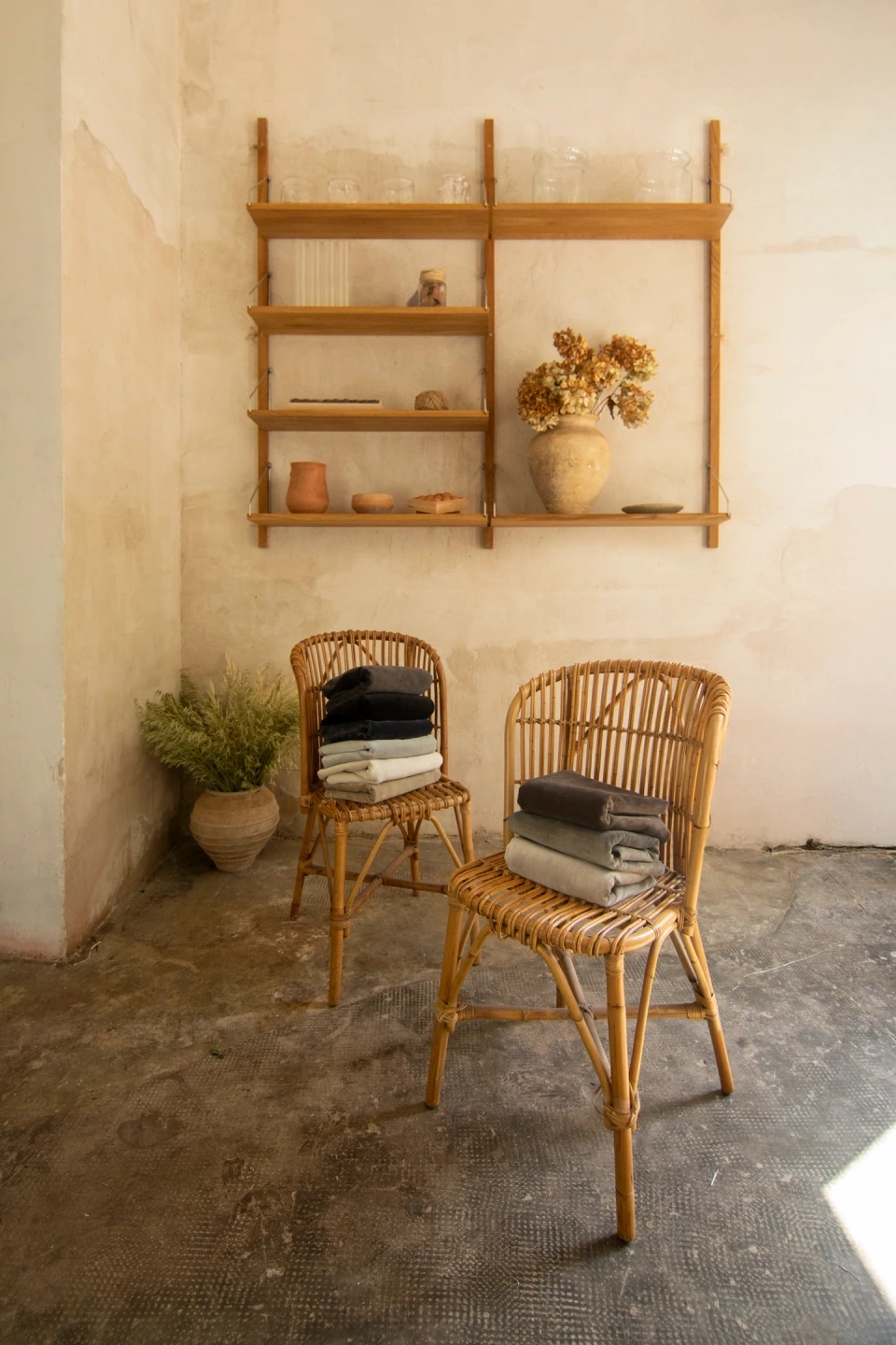 foto de la Colección Natural linen velvet de Les Créations de la Maison Collection de Grupo Lamadrid. Dos sillas con telas encima de la colección, una estantería de fondo en un entorno beige cálido.