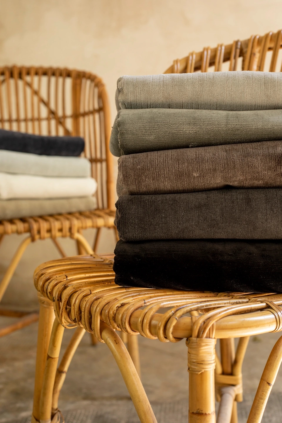 foto de la Colección Natural linen velvet de Les Créations de la Maison Collection de Grupo Lamadrid. Detalle de las dos sillas con telas encima de la colección, una estantería de fondo en un entorno beige cálido.