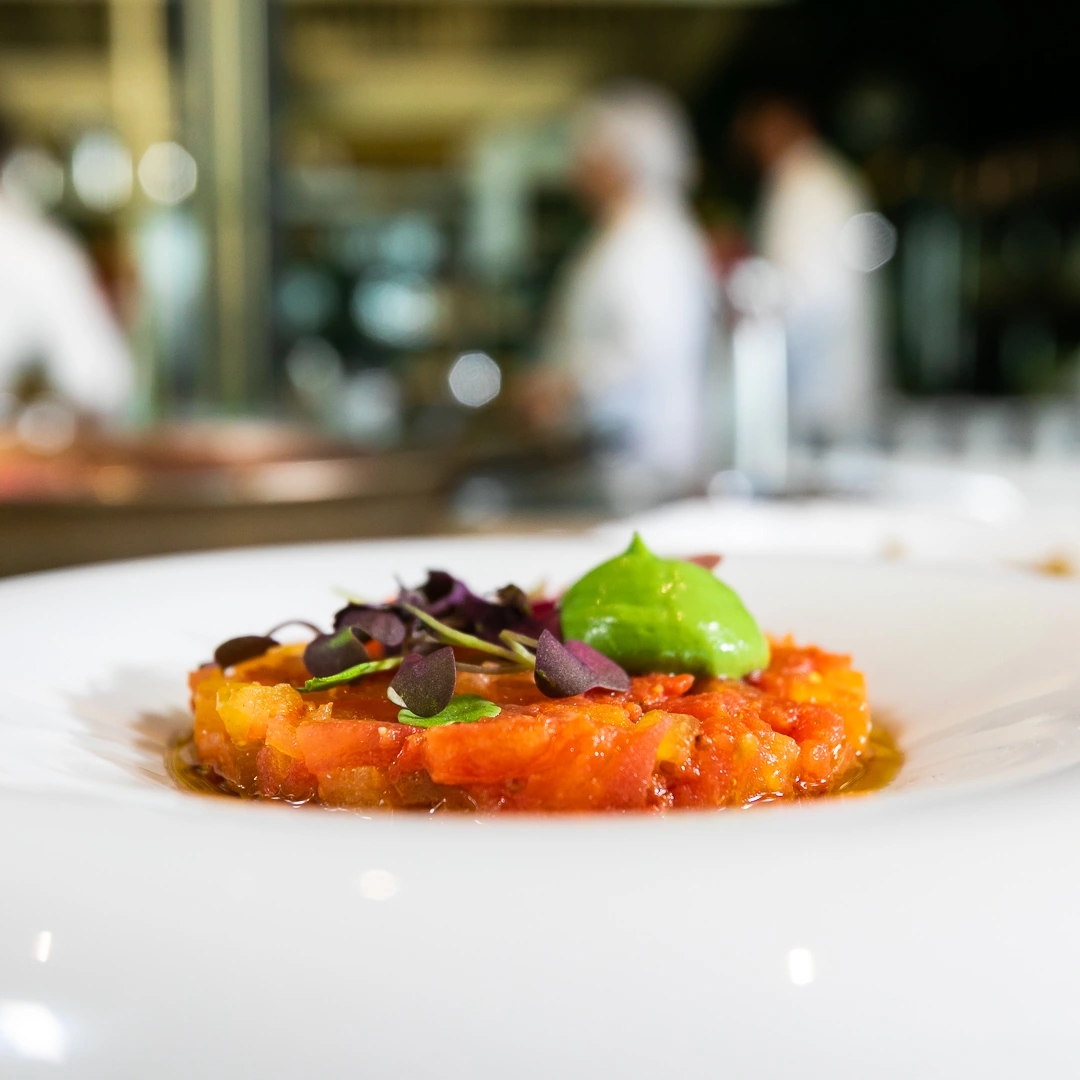 plato de tartar de salmón con cocina de fondo