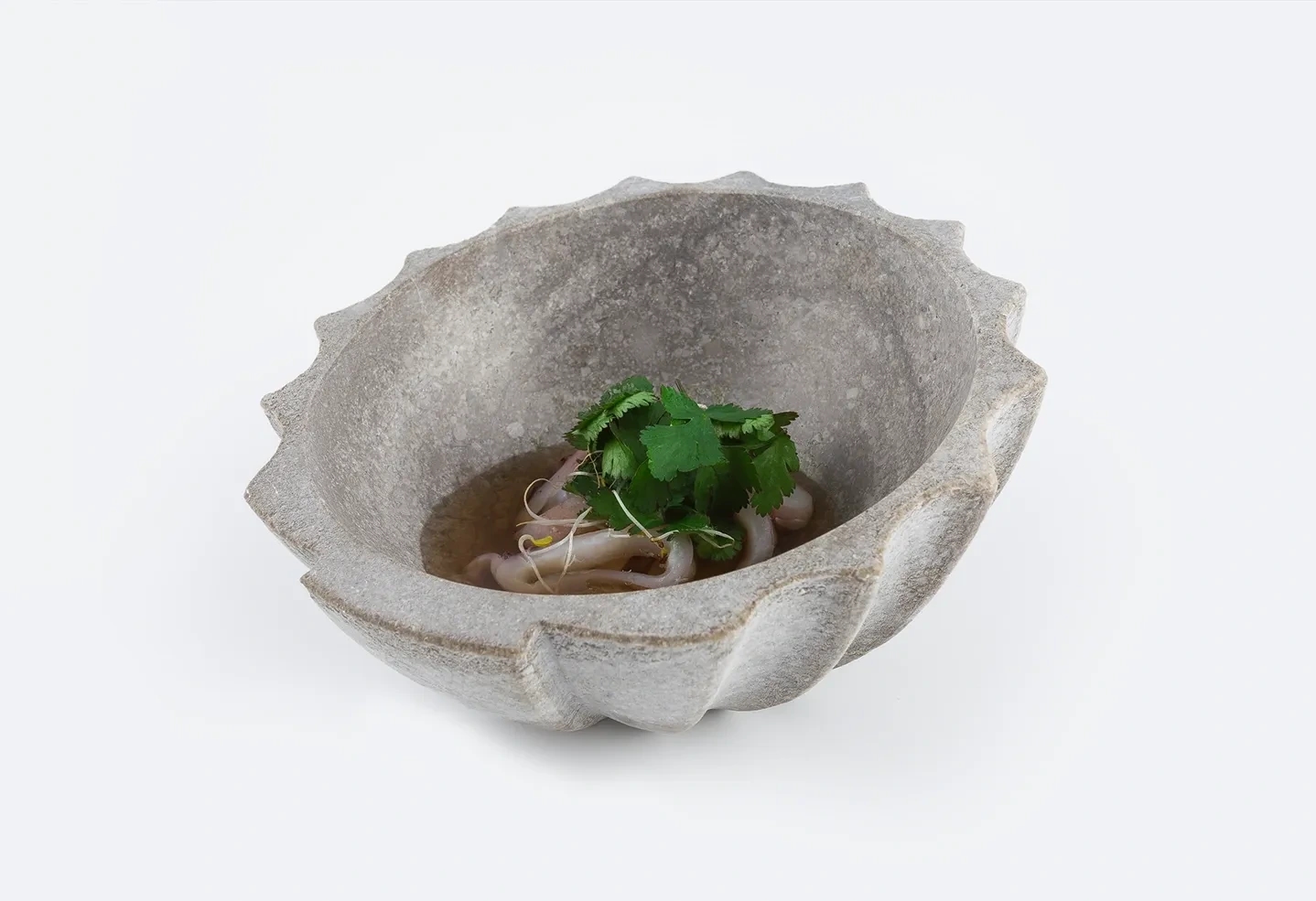 Bol de piedra con un plato asiático cocinado por Martin Lippo en fondo blanco.