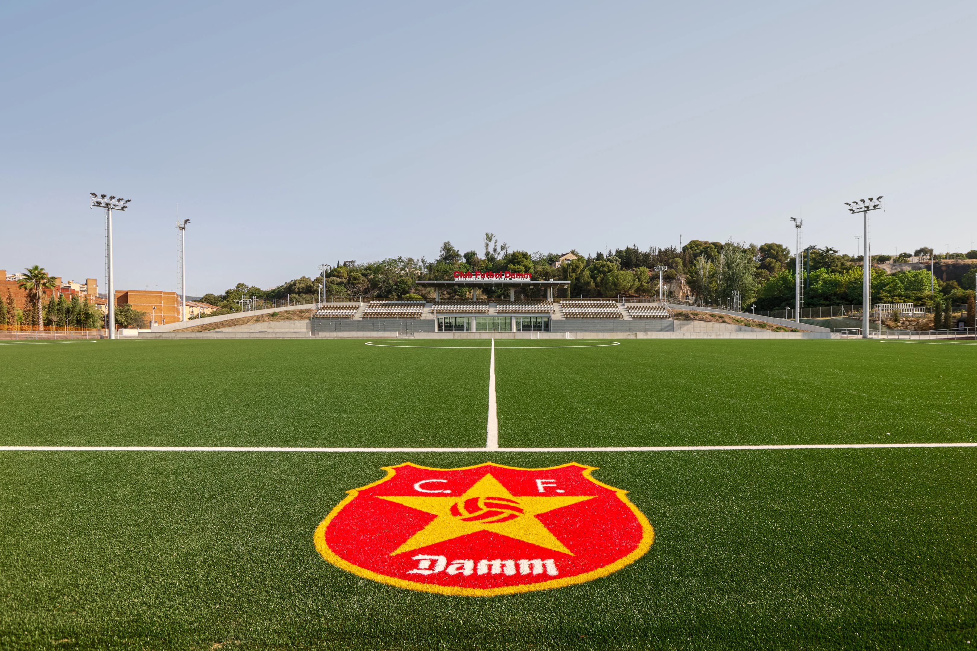 Club de futbol Damm en Montjuïc, Barcelona. Logo del club en primer plano en el césped.