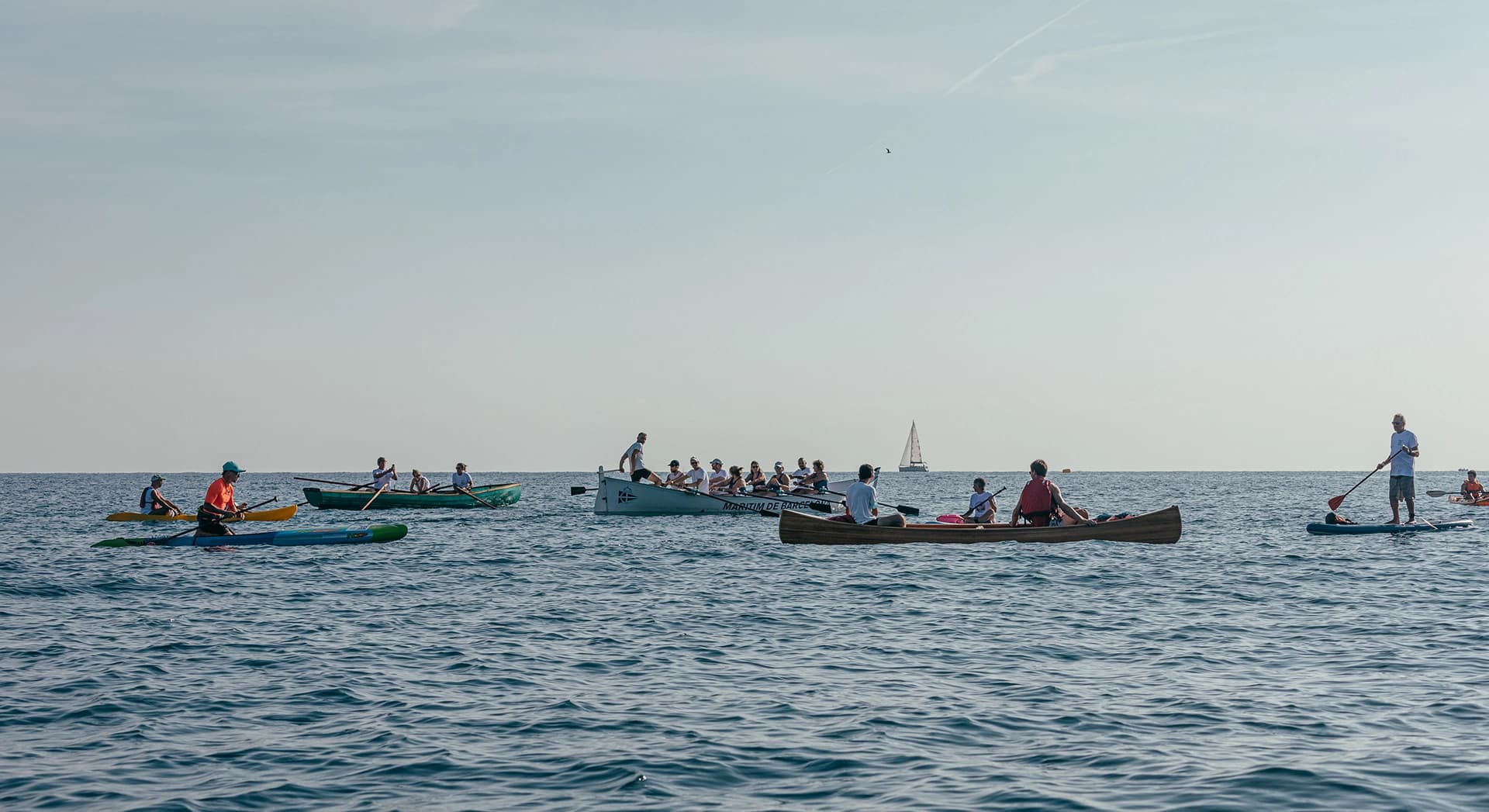 Fotografía de todas las barcas esperando en el mar. Reportaje fotográfico de la Regatta Iomramh, regata irlandesa anual de St. Patrick’s Day en el puerto de Barcelona.