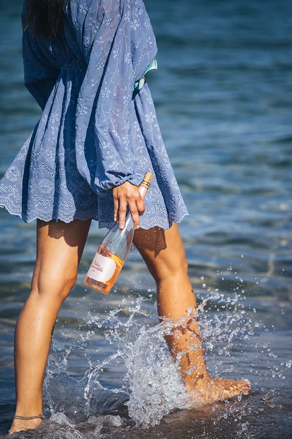 @Elenamarisa caminando por la playa con la botella de Viña Esmeralda mediterranean.