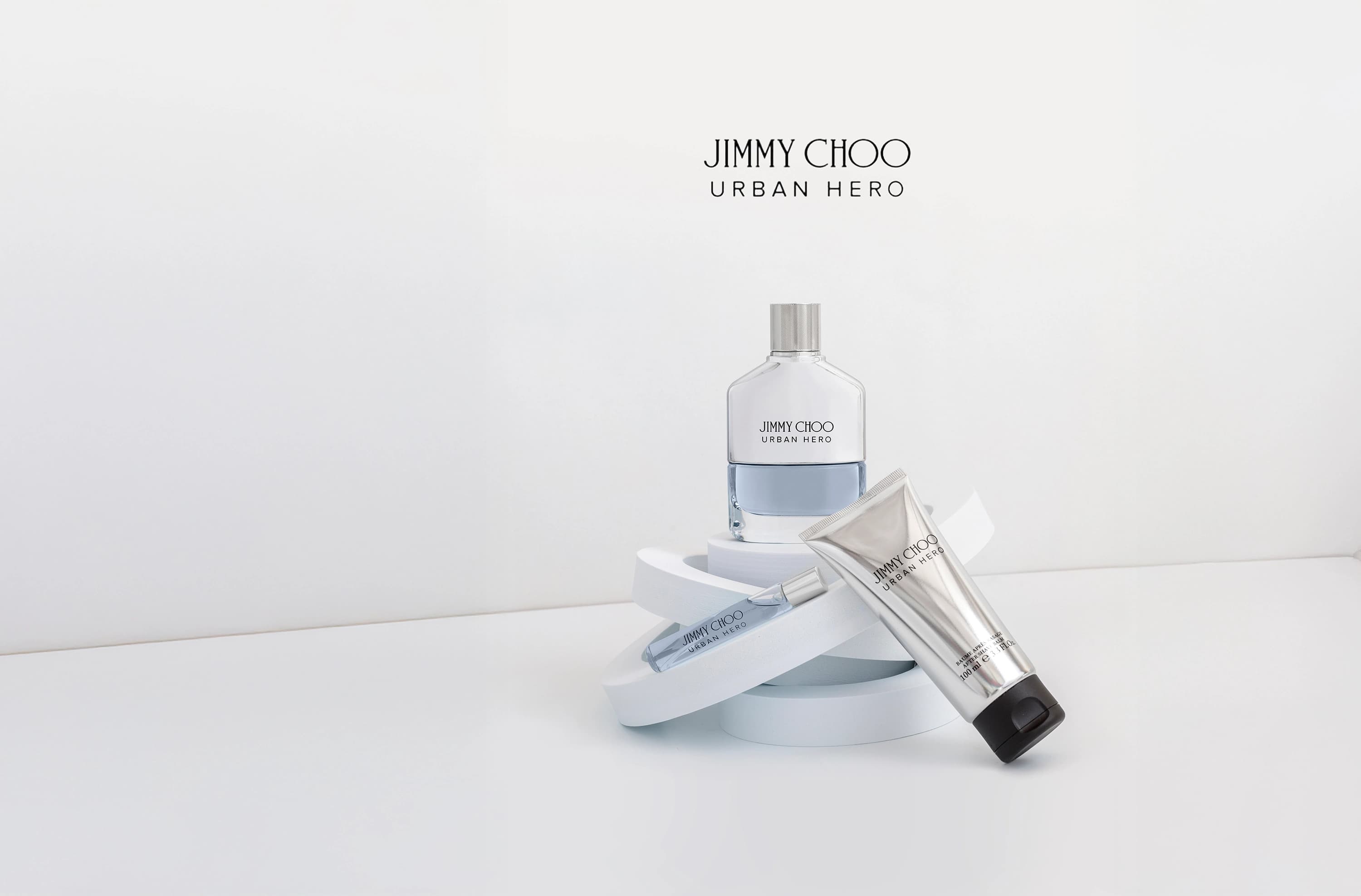 Composición de perfume Jimmy Choo Urban Hero, con el perfume, el perfume de viaje y el bálsamo post afeitado en fondo blanco. Fotografía para la marca Éclair Perfumerías.