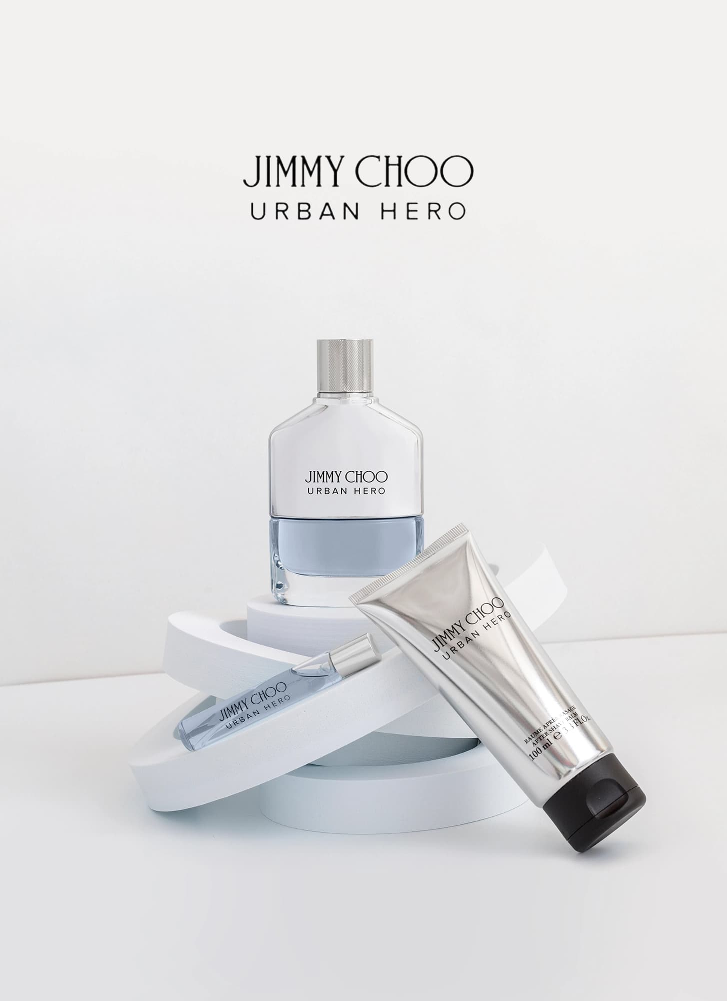 Composición de perfume Jimmy Choo Urban Hero, con el perfume, el perfume de viaje y el bálsamo post afeitado en fondo blanco. Fotografía para la marca Éclair Perfumerías.