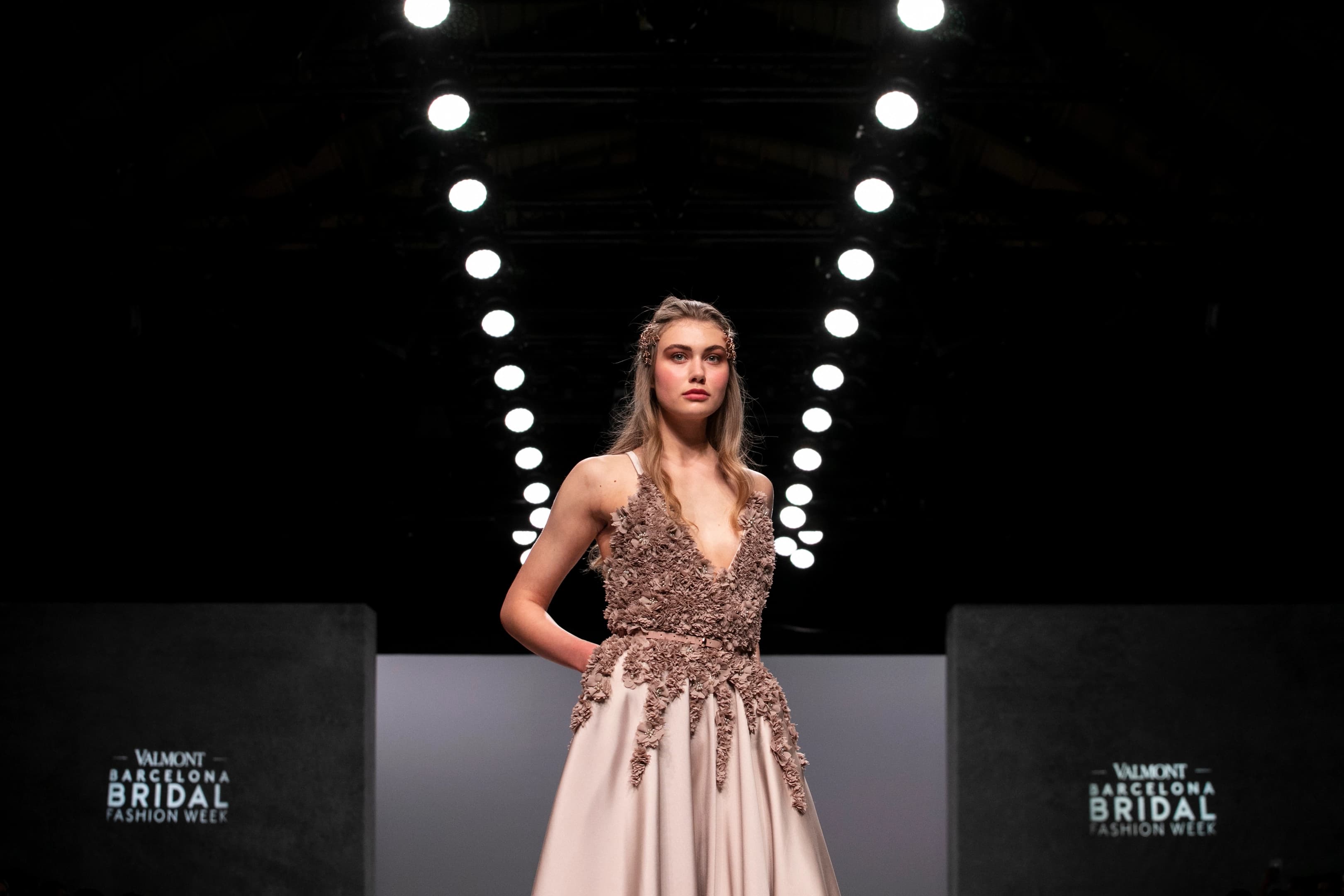Modelo rubia mujer posando de frente con su vestido de novia color beige en el desfile de Sedomir Rodríguez de la Sierra para la pasarela de Barcelona Bridal Fashion Week.