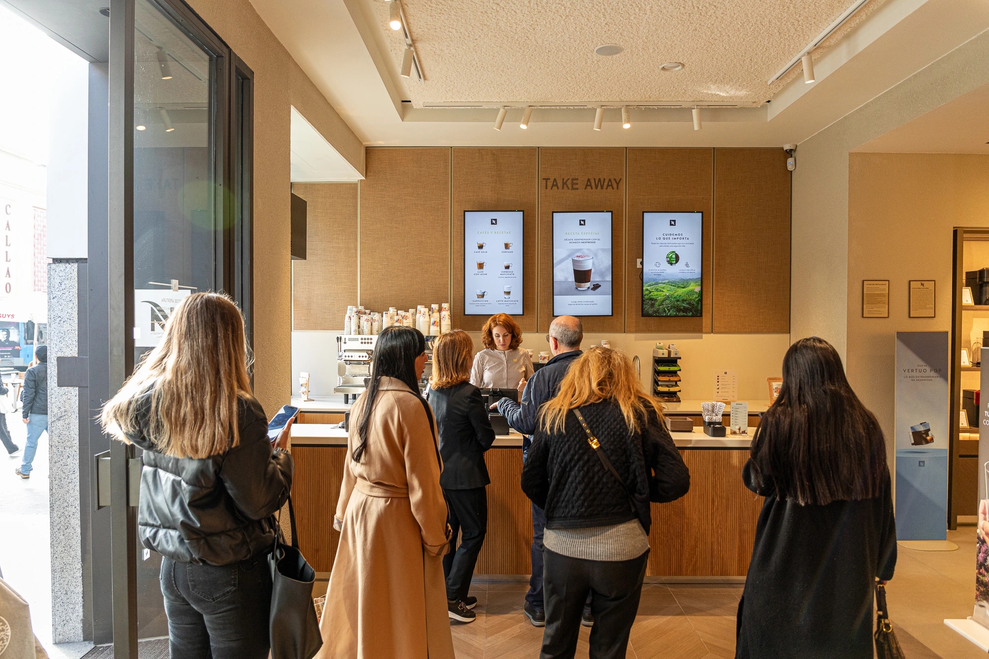 Mujer detrás del mostrador atendiendo a personas en la tienda Nespresso gran vía de Madrid.