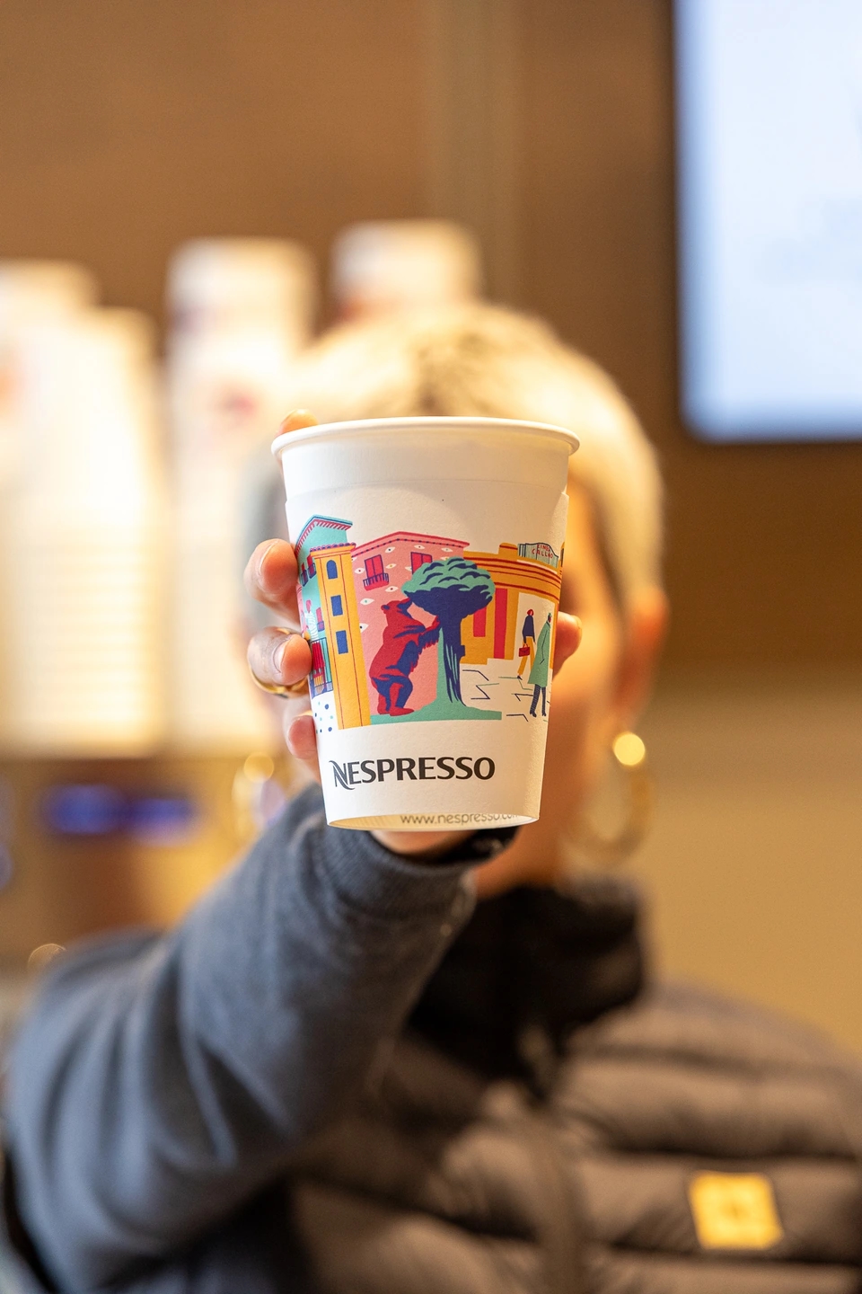 Mujer enseñando una taza de café Nespresso.