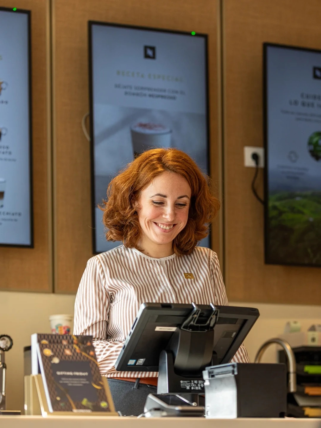 Mujer sonriendo detrás de la caja en la tienda Nespresso gran vía de Madrid