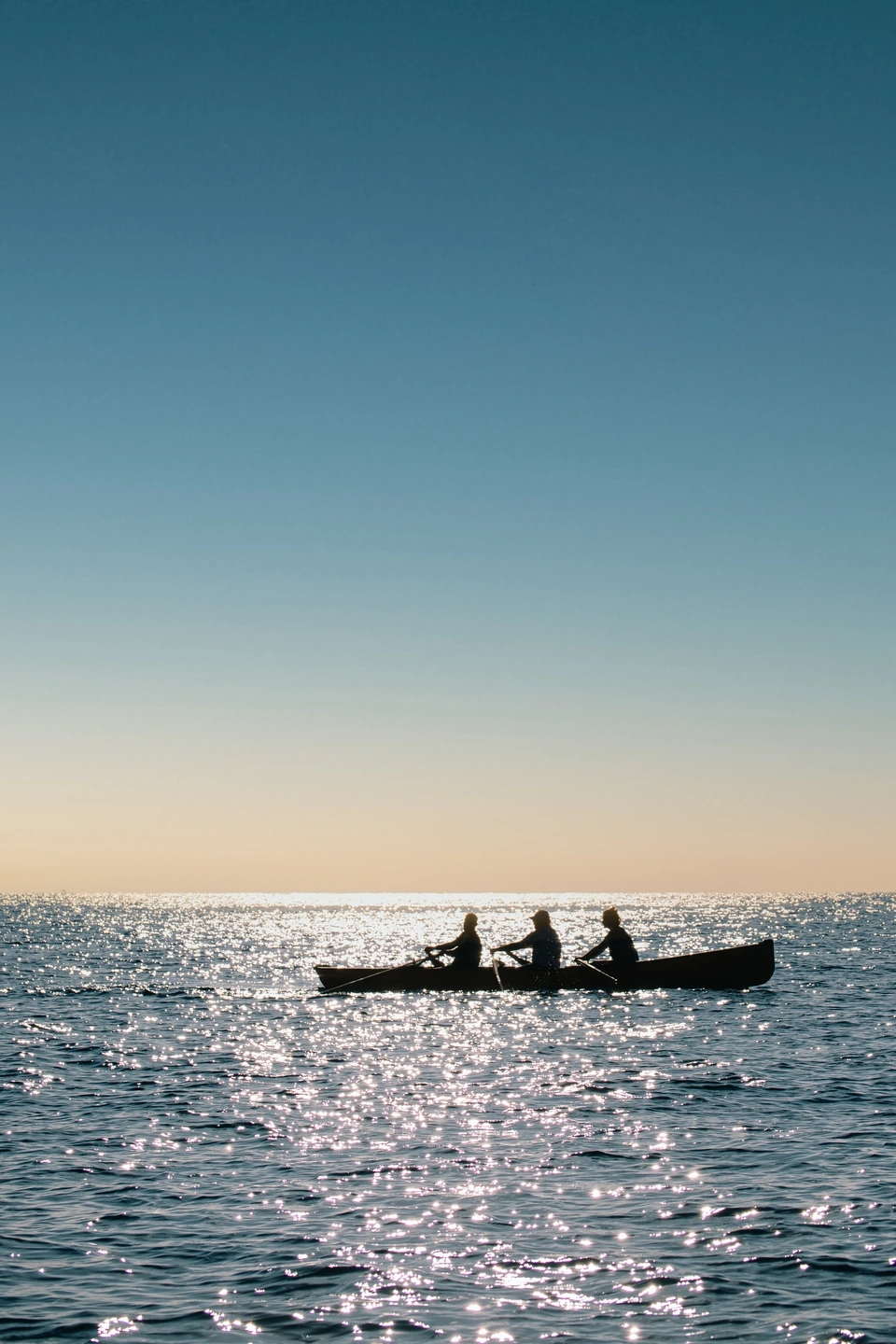 Fotografía de una barca a contraluz remando en el mar. Reportaje fotográfico de la Regatta Iomramh, regata irlandesa anual de St. Patrick’s Day en el puerto de Barcelona.