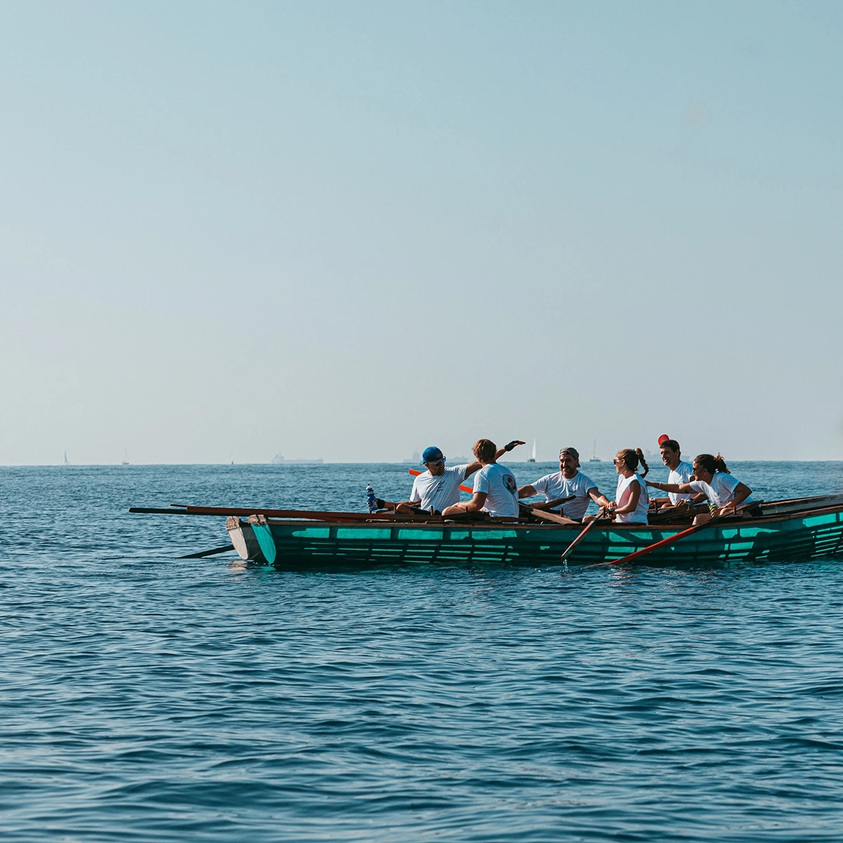 Fotografía de la barca esperando en el mar. Reportaje fotográfico de la Regatta Iomramh, regata irlandesa anual de St. Patrick’s Day en el puerto de Barcelona.