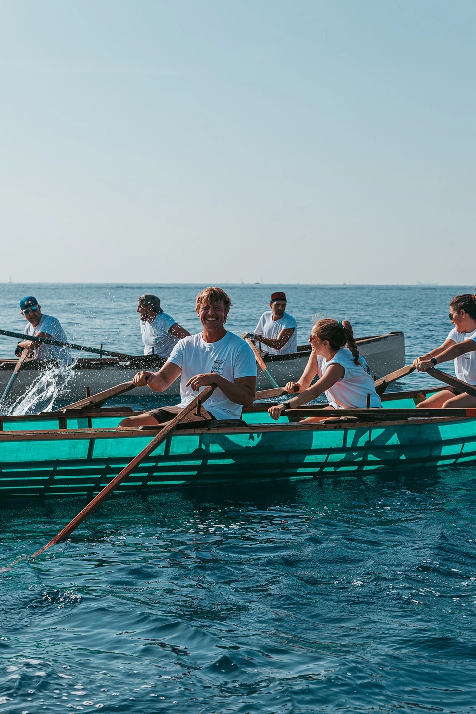 Fotografía de un hombre riiendo en el currach que ha construido en el mar. Reportaje fotográfico de la Regatta Iomramh, regata irlandesa anual de St. Patrick’s Day en el puerto de Barcelona.