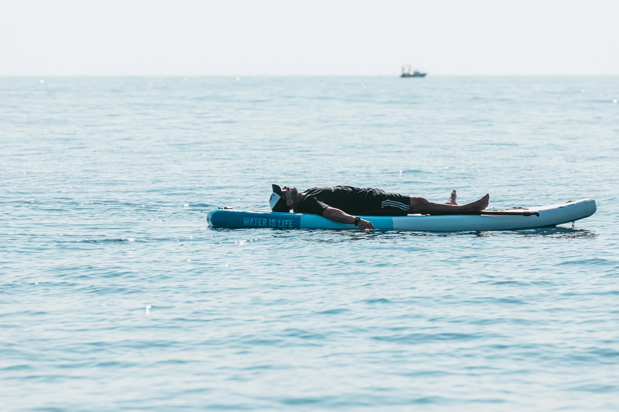 Fotografía paddle y un hombre descansando en el mar. Reportaje fotográfico de la Regatta Iomramh, regata irlandesa anual de St. Patrick’s Day en el puerto de Barcelona.