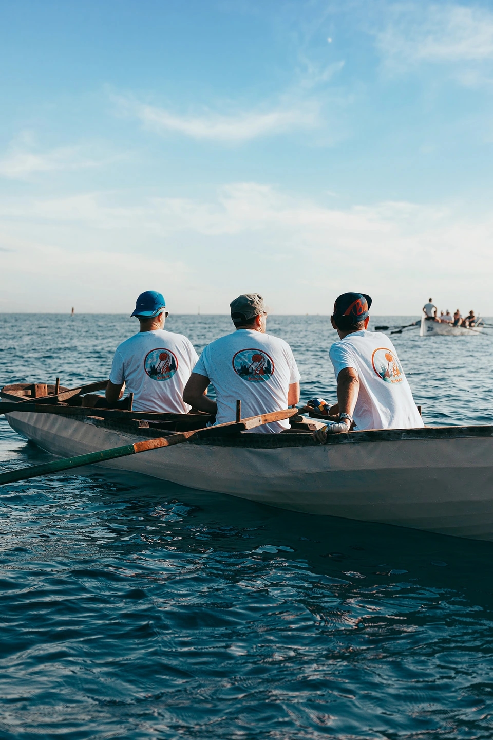 Fotografía 3 remeros en un currach esperando en el mar. Reportaje fotográfico de la Regatta Iomramh, regata irlandesa anual de St. Patrick’s Day en el puerto de Barcelona.