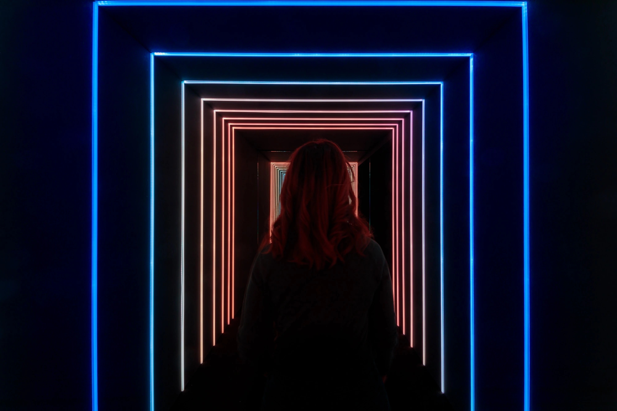 mujer caminando en un túnel iluminado por neones de colores. Efecto estroboscópico.