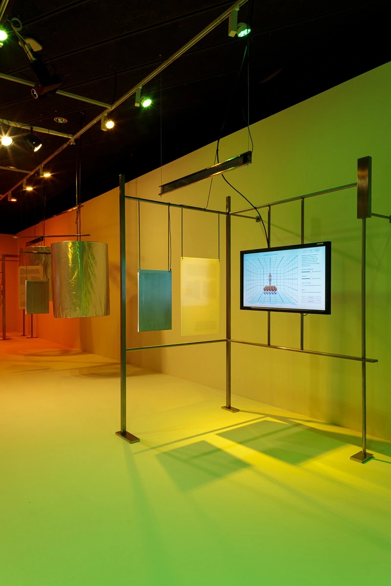Fotografia de la escenografia de la exposición de Nueva pantalla, el videojuego en Cataluña. Fondo verde y una pantalla de televisión enseñando demos