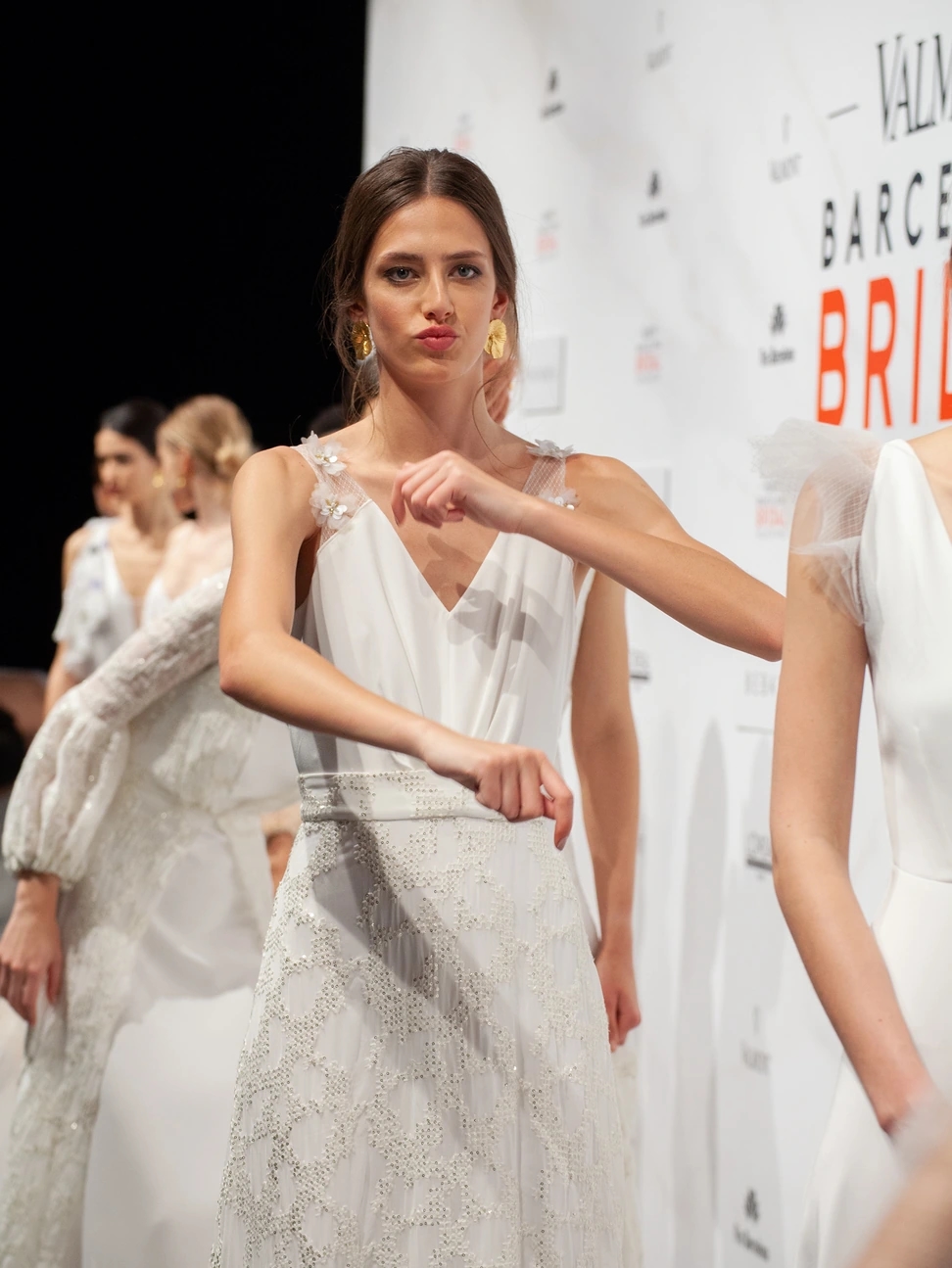 Modelo con vestido helenístico haciendo un bailecito con las manos, soltando los nervios en el backstage del desfile de Beba's en la Barcelona Bridal Fashion Week.