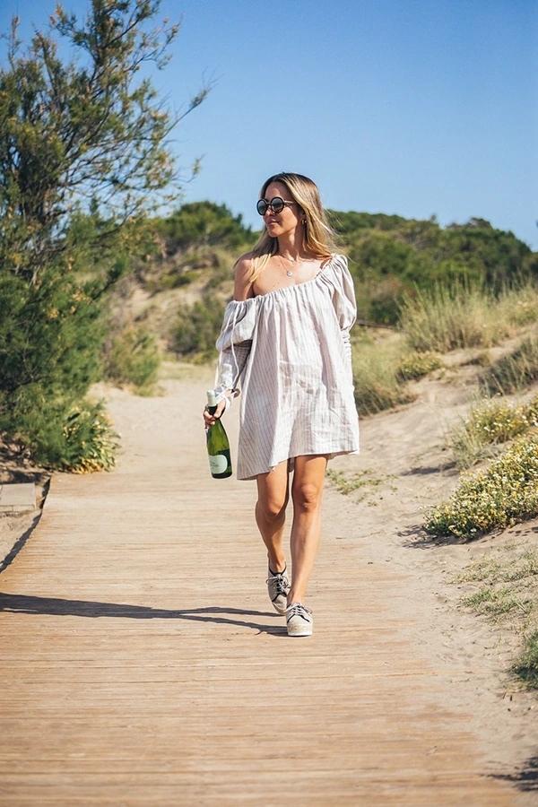 Mujer caminando cerca de la playa con una botella de Viña Esmeralda mediterranean.