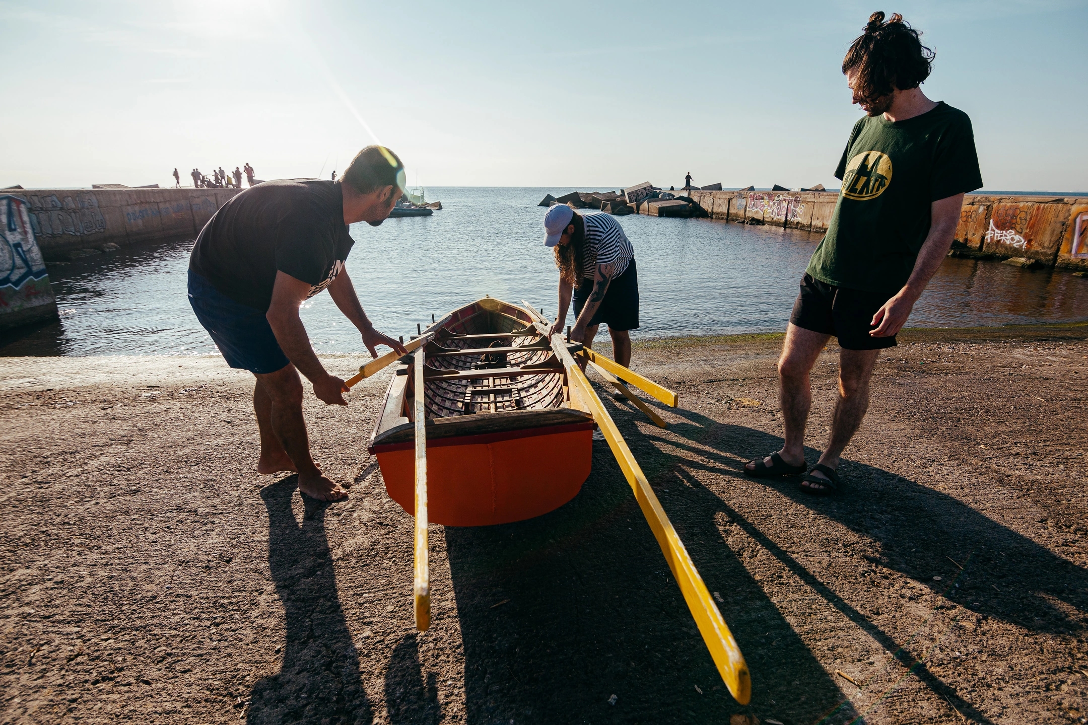 Fotografía de dos remeros recogiendo el currach. Reportaje fotográfico de la Regatta Iomramh, regata irlandesa anual de St. Patrick’s Day en el puerto de Barcelona.