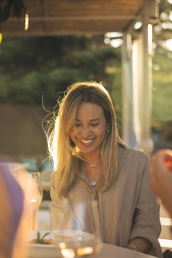 Mujer sonriendo tímidamente al atardecer con luz espectacular.