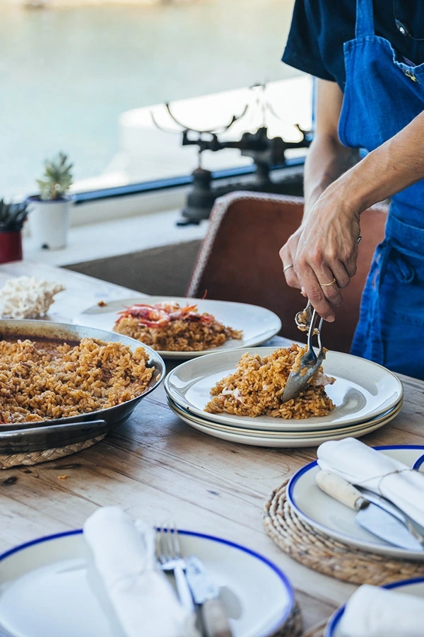 Camarera preparando la paella en un restaurante de la costa brava. Viña Esmeralda mediterranean.