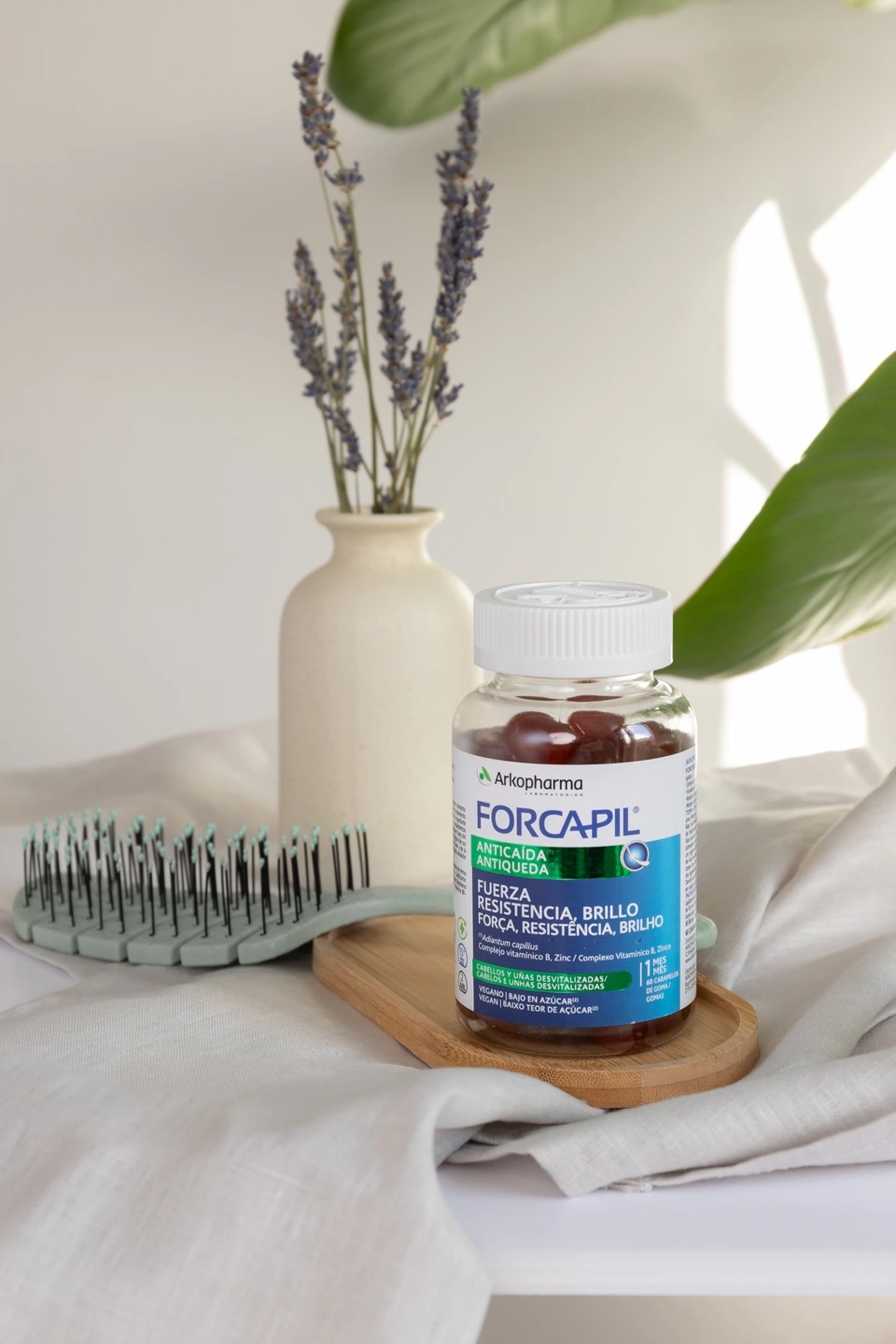 bote de Gummies anticaída capilar con un peine y un jarrón con lavanda de la marca Forcapil, producto de la farmacéutica Arkopharma para una sesión fotográfica creativa en Madrid.
