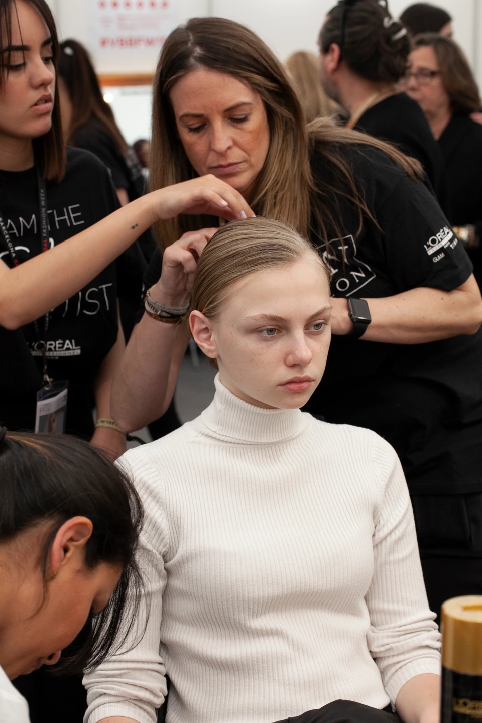 Backstage del desfile de novias AIRE, peluqueras alrededor de la modelo de L'Óreal.