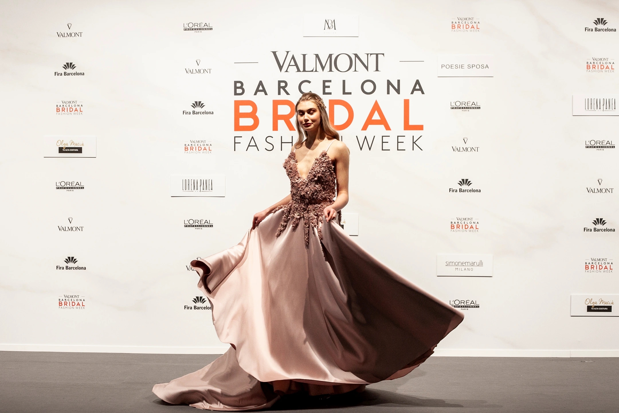 Modelo mujer moviendo su vestido de novia color rosa pálido en el photocall de Sedomir Rodríguez de la Sierra para la pasarela de Barcelona Bridal Fashion Week.