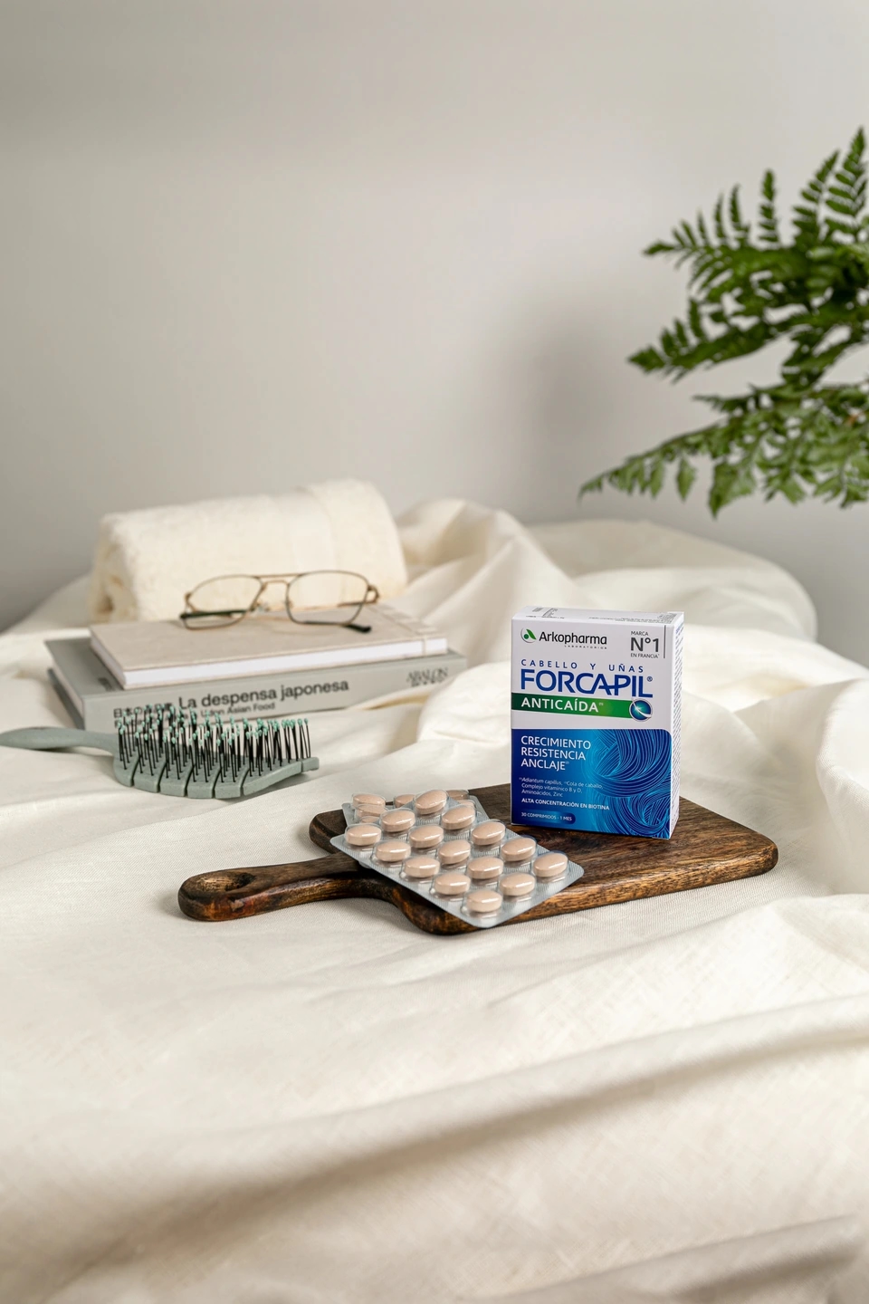 Pastillas anticaída de Forcapil en fondo neutro con un peine y unas gafas de ver, producto de la farmacéutica Arkopharma para una sesión fotográfica creativa en Madrid.