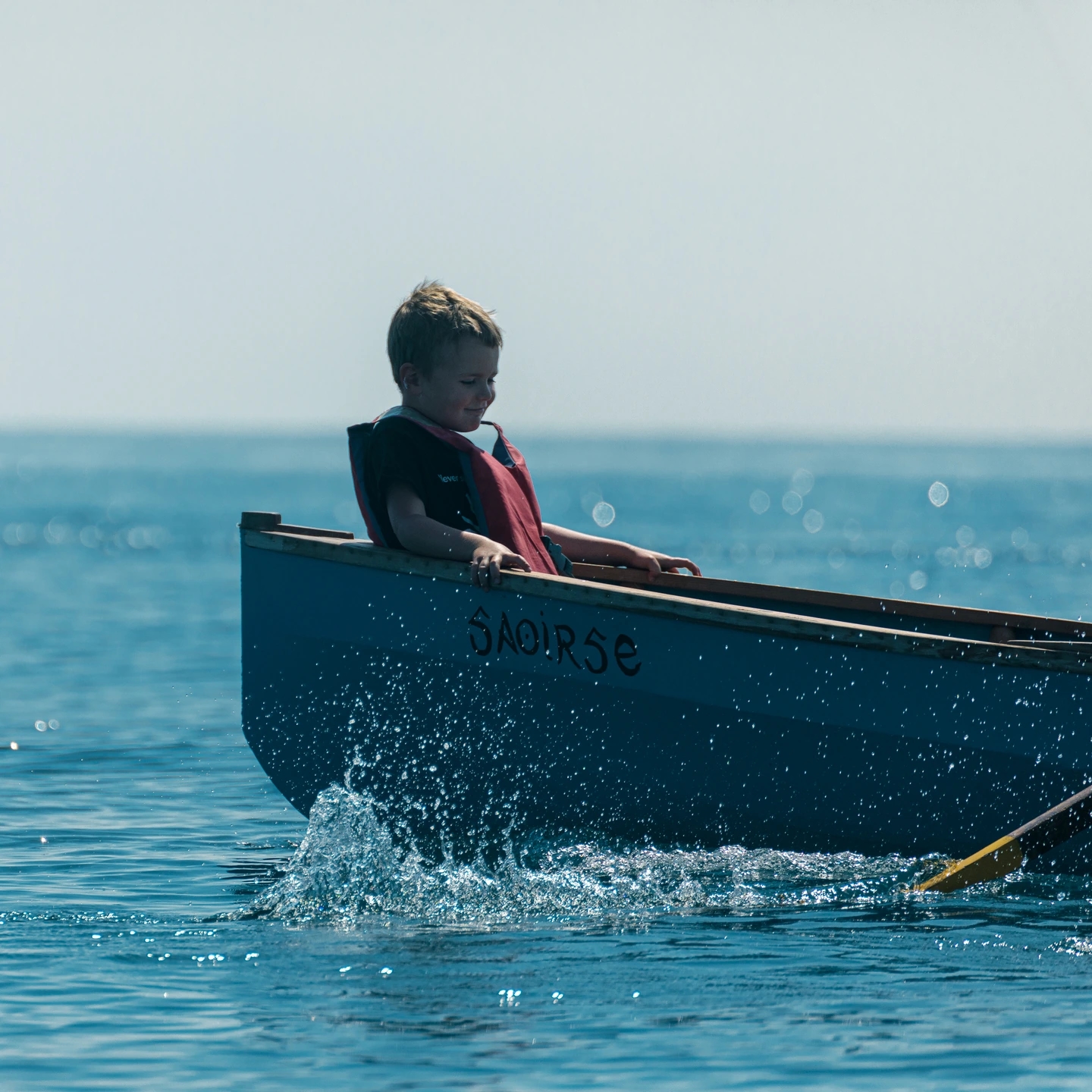 NIño disfrutando en el currach saorise. Reportaje fotográfico de la Regatta Iomramh, regata irlandesa anual de St. Patrick’s Day en el puerto de Barcelona.