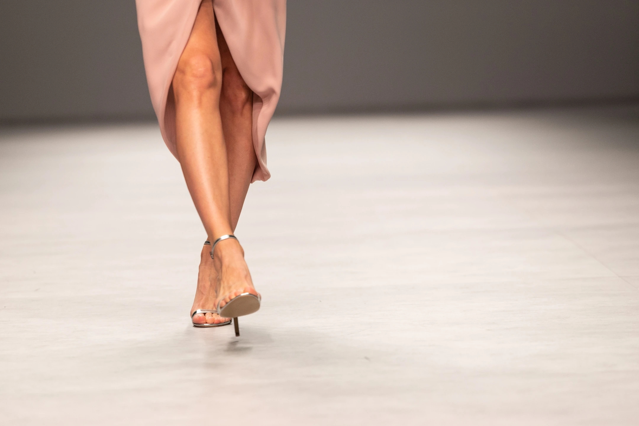 Modelo enseñando los zapatos con vestido de invitada color nude en ell desfile de Cristina Tamborero para la Barcelona Bridal Fashion Week.