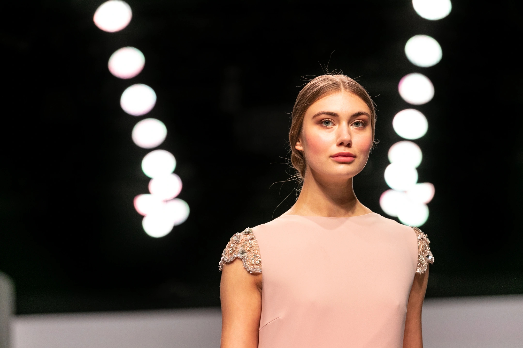 Modelo de cara con vestido de invitada color nude en ell desfile de Cristina Tamborero para la Barcelona Bridal Fashion Week.