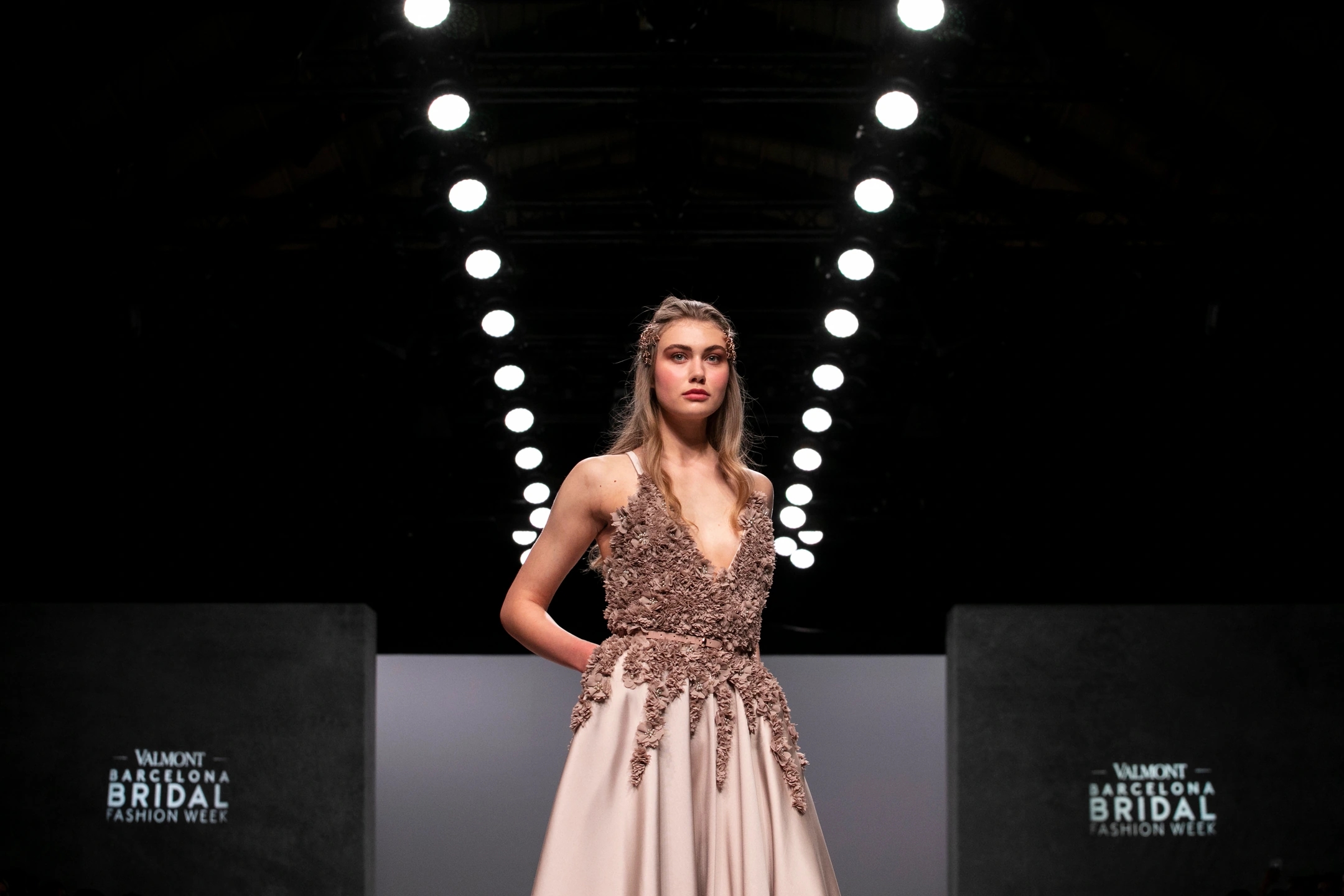 Modelo rubia mujer posando de frente con su vestido de novia color beige en el desfile de Sedomir Rodríguez de la Sierra para la pasarela de Barcelona Bridal Fashion Week.