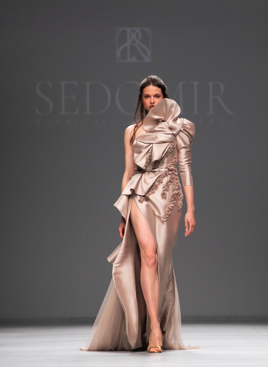 Modelo mujer andando de frente con su vestido de novia color crema café en el desfile de Sedomir Rodríguez de la Sierra para la pasarela de Barcelona Bridal Fashion Week.
