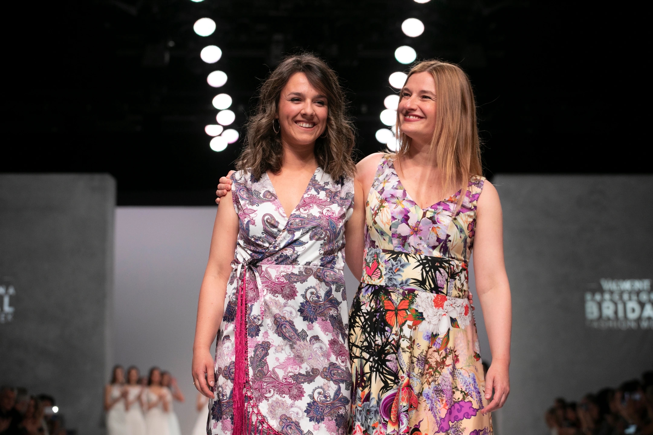 Diseñadoras de María Salas para la Barcelona Bridal Fashion Week posando delante de cámara con las modelos detrás aplaudiendo al final del desfile.