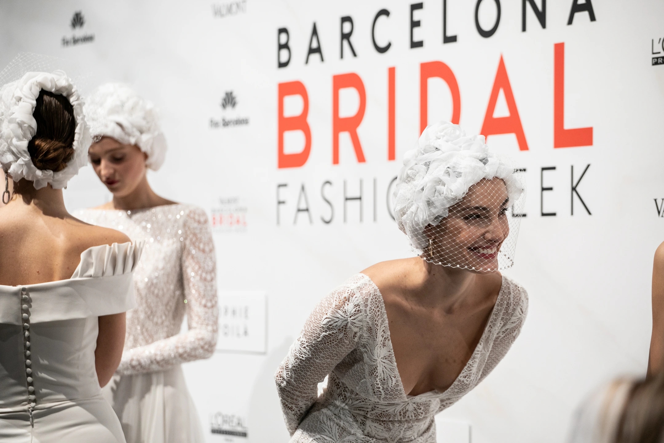 Modelo con vestido de novia sonriendo inclinada hacia delante en el backstage del desfile de Flora para la Barcelona Bridal Fashion Week.