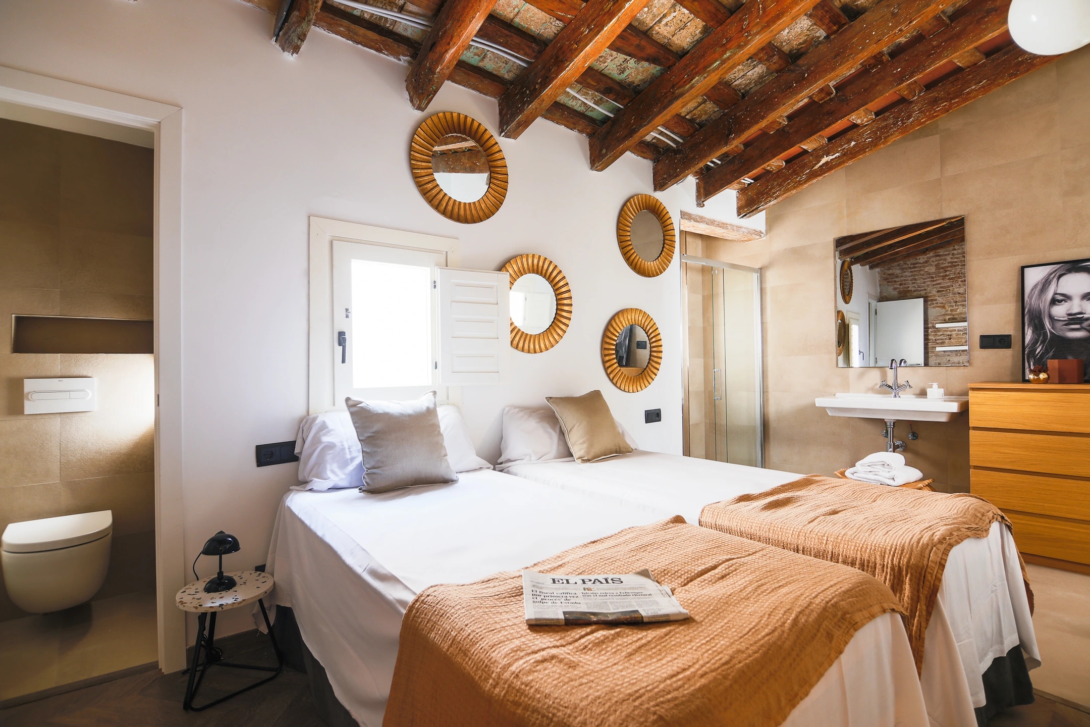 Foto del dormitorio en calle del Carme de Barcelona. Estilo clásico modernista, con estetica actual. Colores marrón suaves y paredes blancas con vigas de madera.